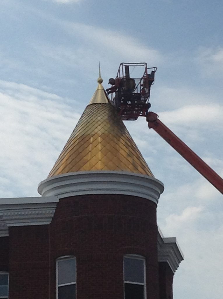 Spenglers working on the copper roof of a house turret