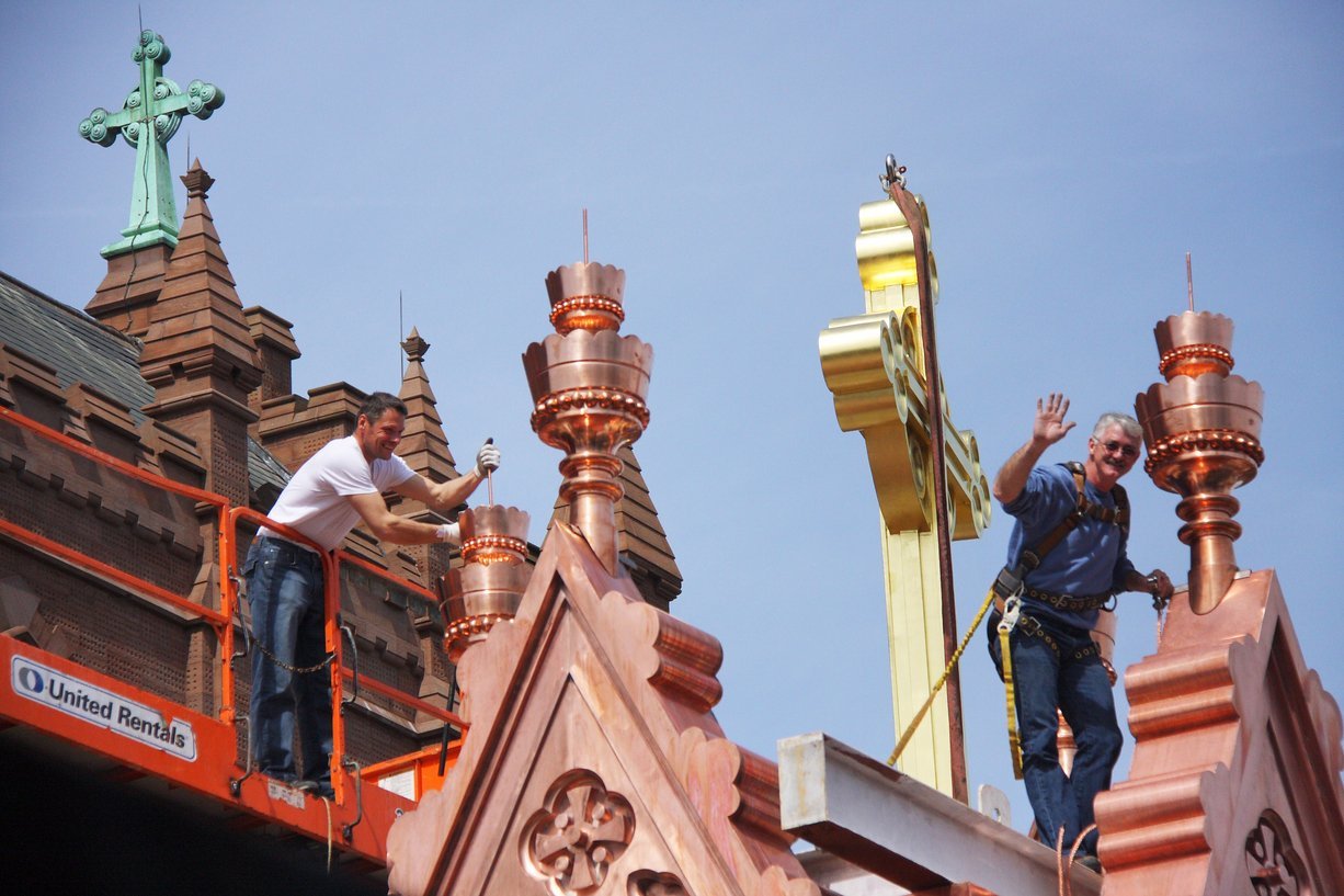 placing gilded cross on church