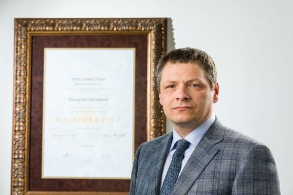 Erno Ovari, Spenglermeister, master of metal roof and wall, stands next to his Meisterbrief.