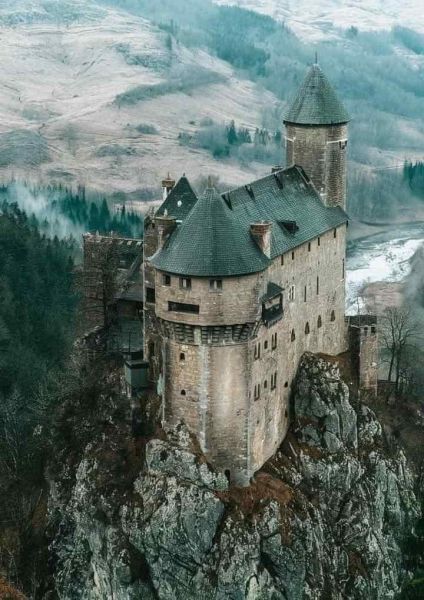 High castle on a steep cliff showcasing European half-round gutters, illustrating the need for durable, low-maintenance roofing solutions on tall, inaccessible buildings